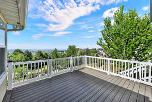 Spacious outdoor deck featuring gray composite decking, white railing, and a broad landscape vista