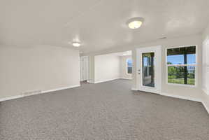 Spacious room with grey patterned carpeting, light neutral wall paint, and white trim