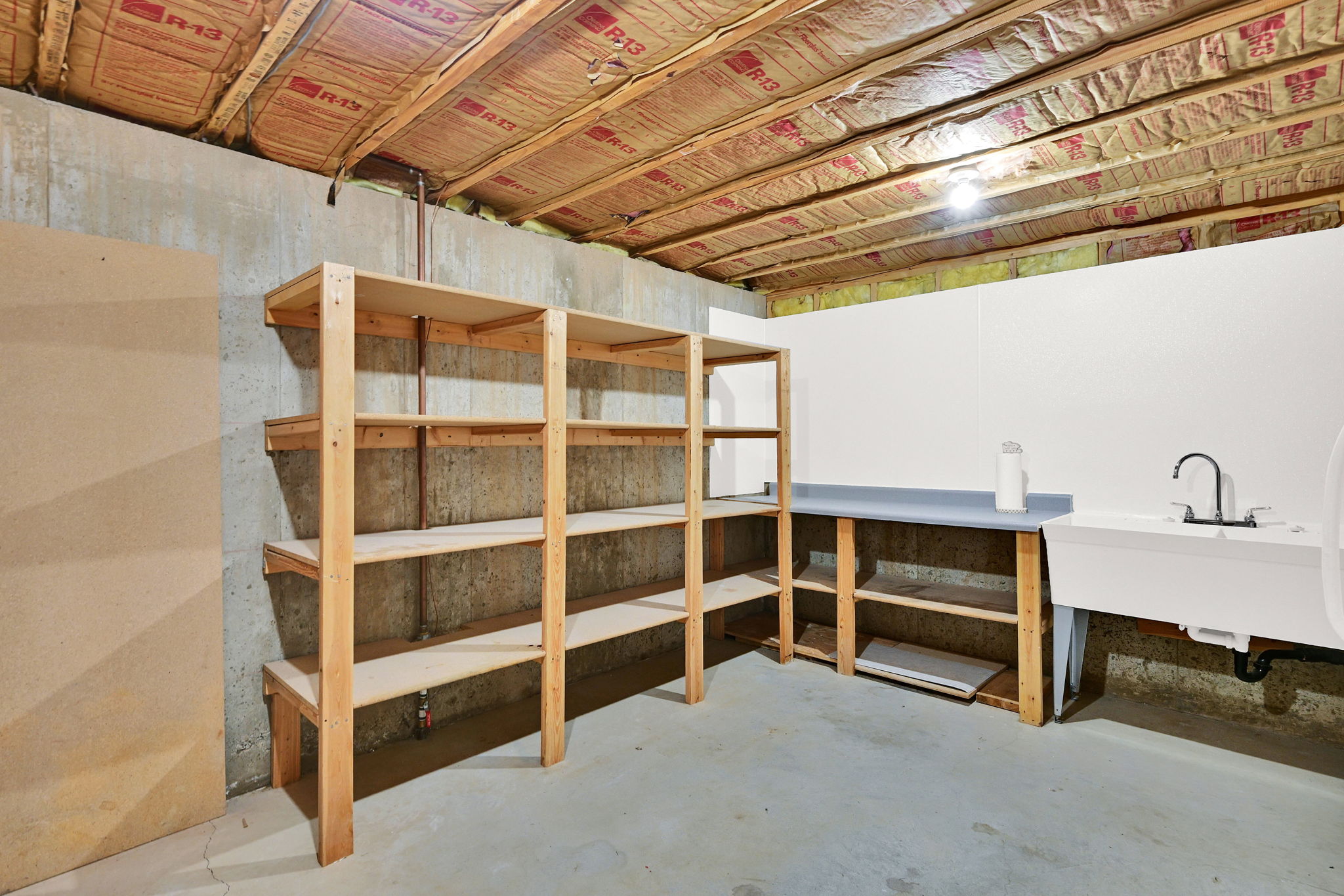 Unfinished basement space featuring concrete foundation walls and exposed ceiling joists with insulation