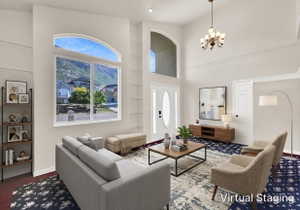 Grand living room featuring an arched transom window, high ceilings, crown molding, and a prominent chandelier