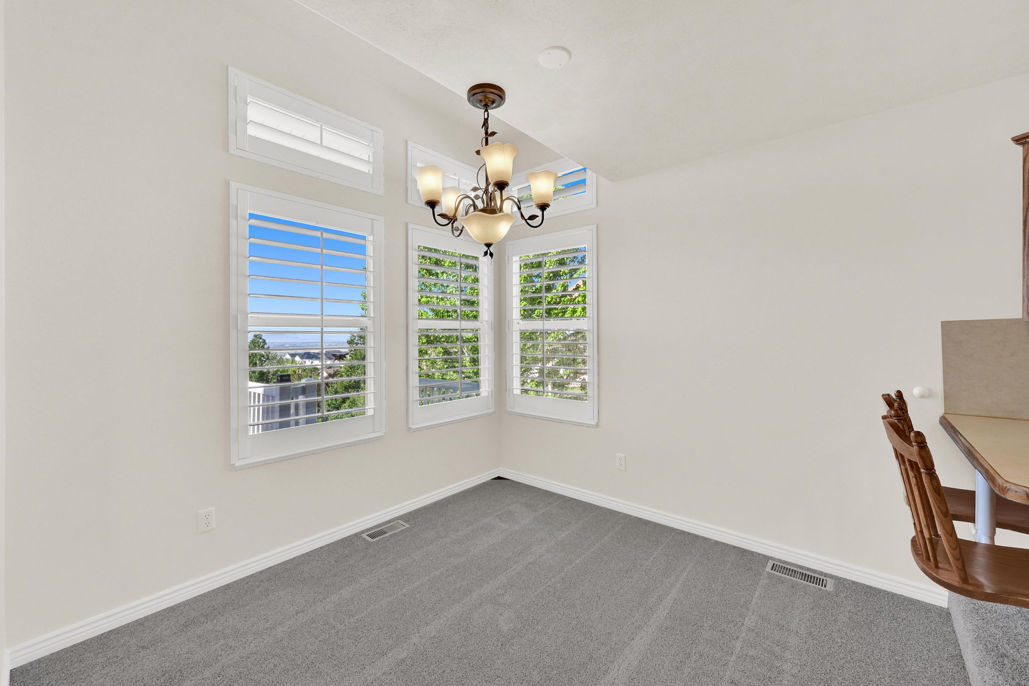 Dining area featuring a classic chandelier and multiple windows with plantation shutters