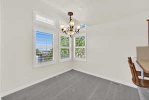 Dining area featuring a classic chandelier and multiple windows with plantation shutters