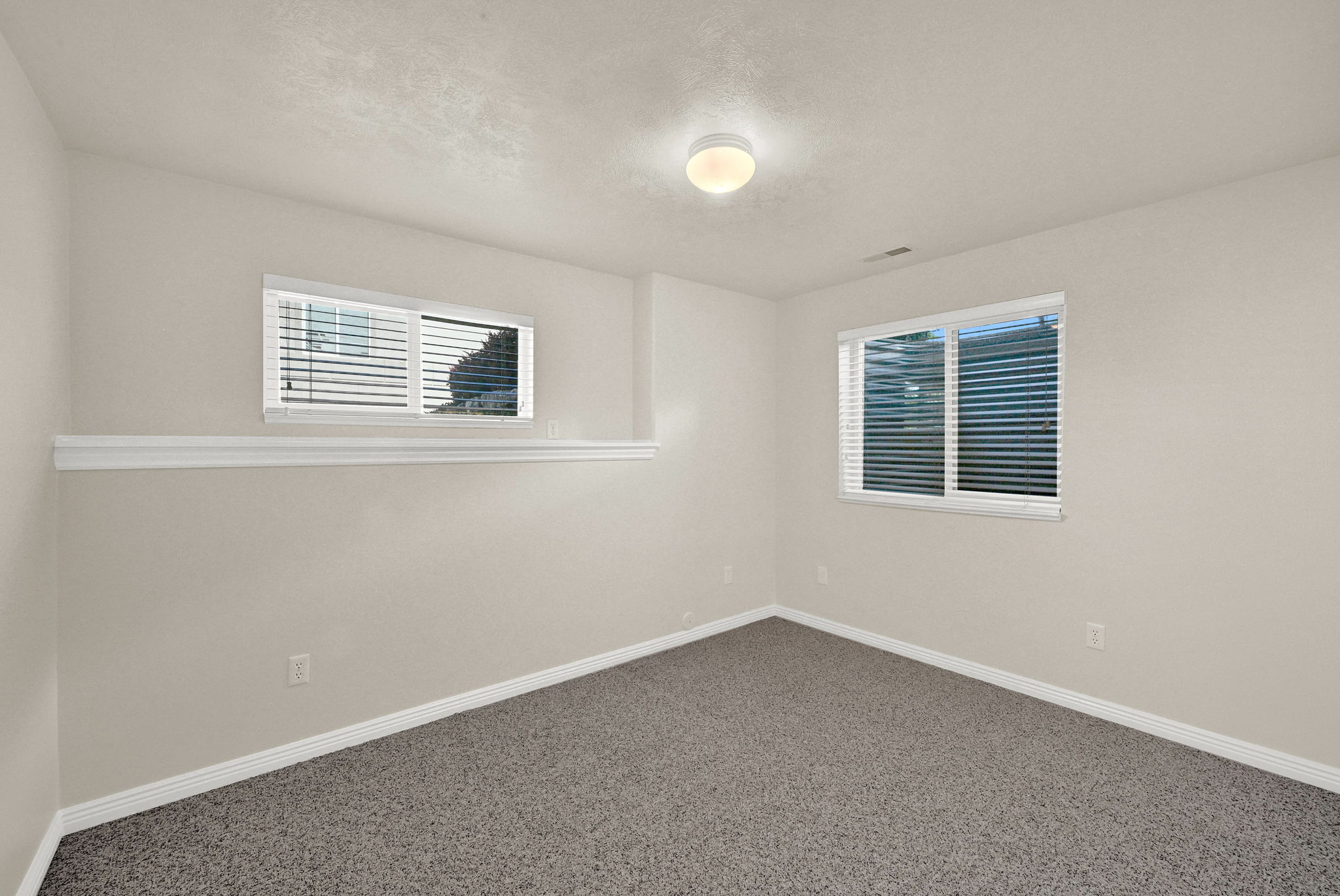 Spacious room featuring neutral paint, gray textured carpet, and white baseboards