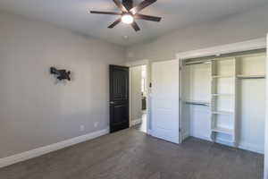 Carpeted room featuring a ceiling fan with integrated lighting, a black paneled door, and a built-in closet with shelving and hanging rods