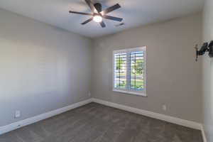 Bedroom featuring a ceiling fan with integrated lighting, a window with plantation shutters, neutral-toned walls, and grey carpeting