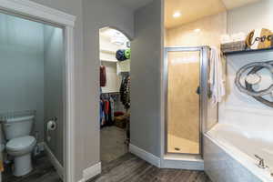 Bathroom with walk-in shower, soaking tub, private commode, and an arched entry to a walk-in closet