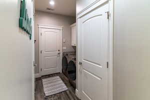 Laundry area featuring wood-finish flooring, white cabinetry, a recessed light fixture, and white interior doors with decorative trim
