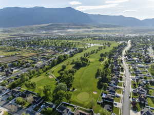 Expansive aerial perspective showcasing a residential community bordering a golf course with mature trees and water features