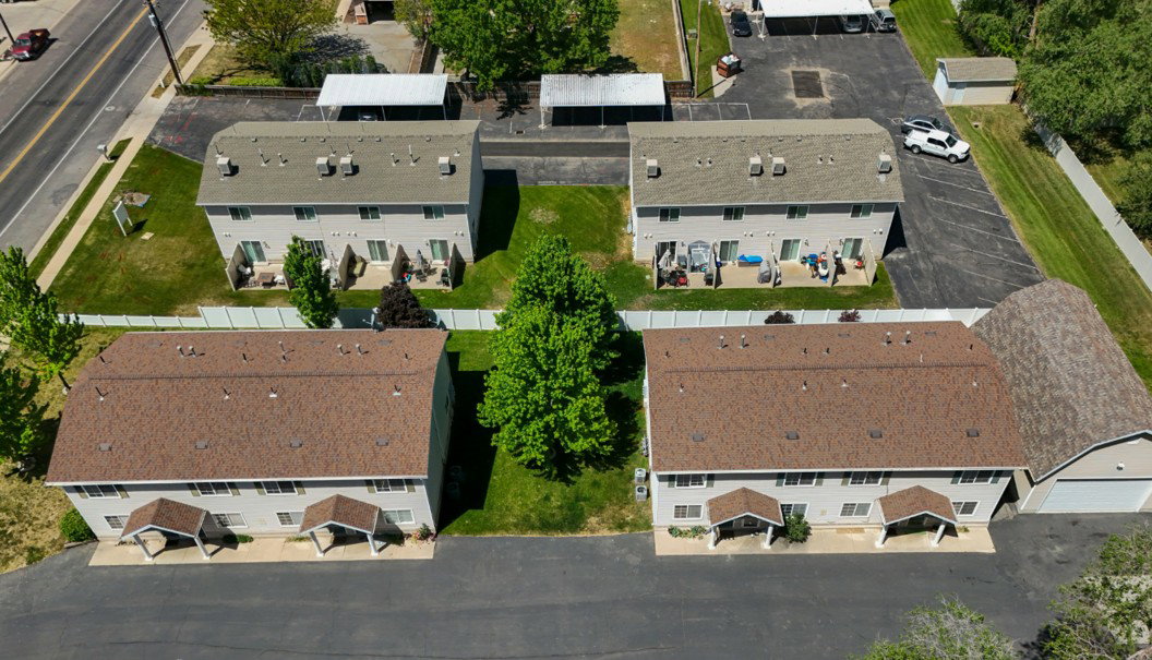 Four multi-unit residential buildings with light-toned siding and brown shingled roofs