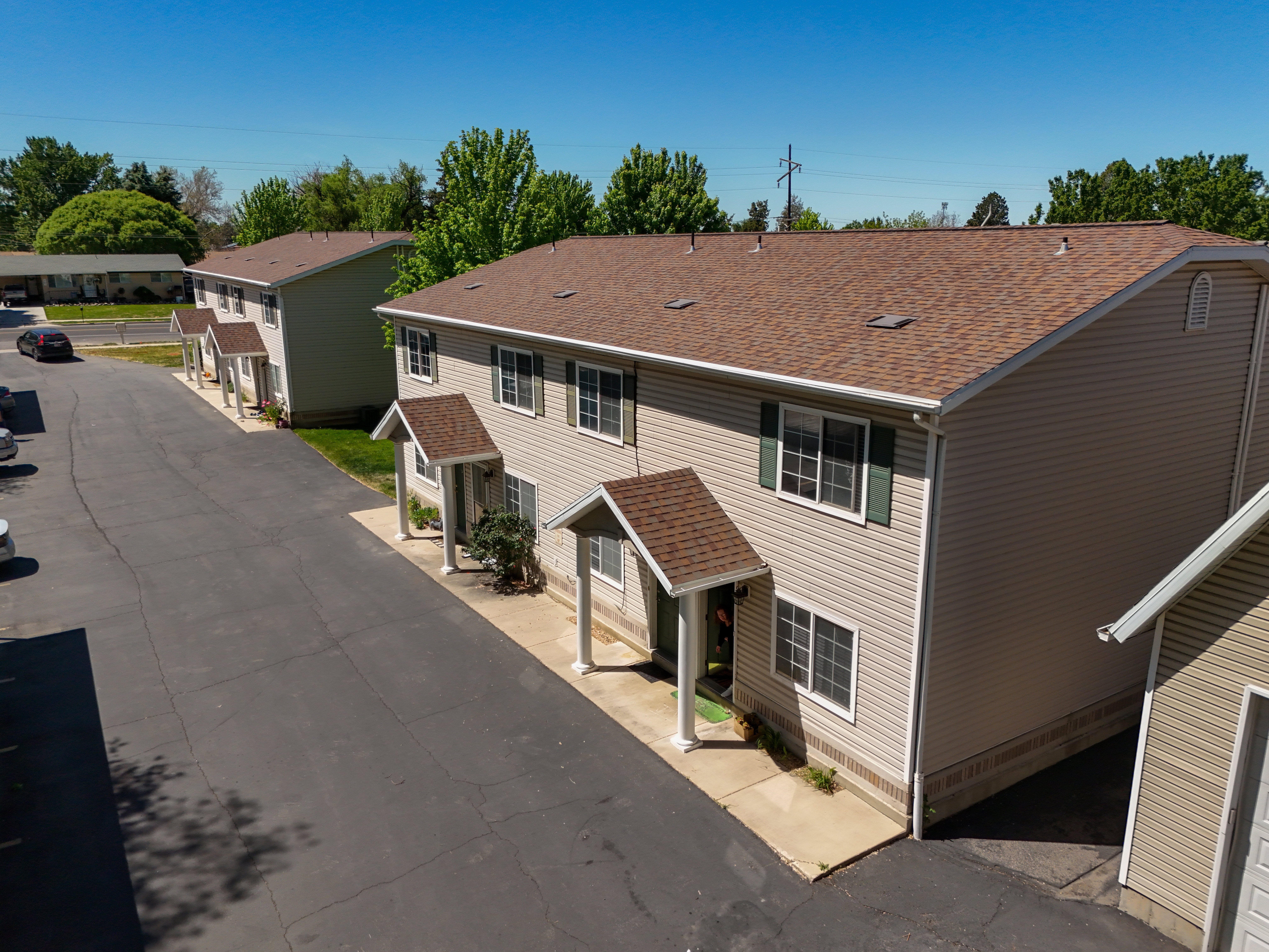 Multi-unit residential property featuring tan horizontal siding and dark brown shingle roofing