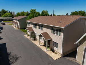 Multi-unit residential property featuring tan horizontal siding and dark brown shingle roofing