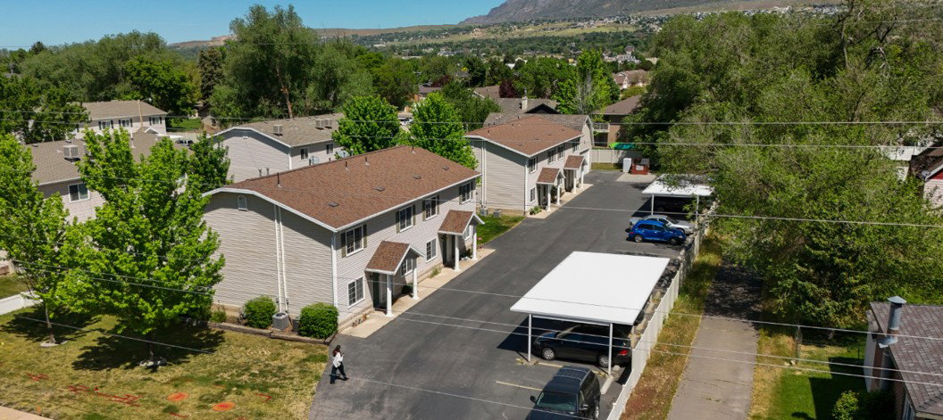 Multi-building property featuring light gray siding, brown shingle roofing, and covered entryways