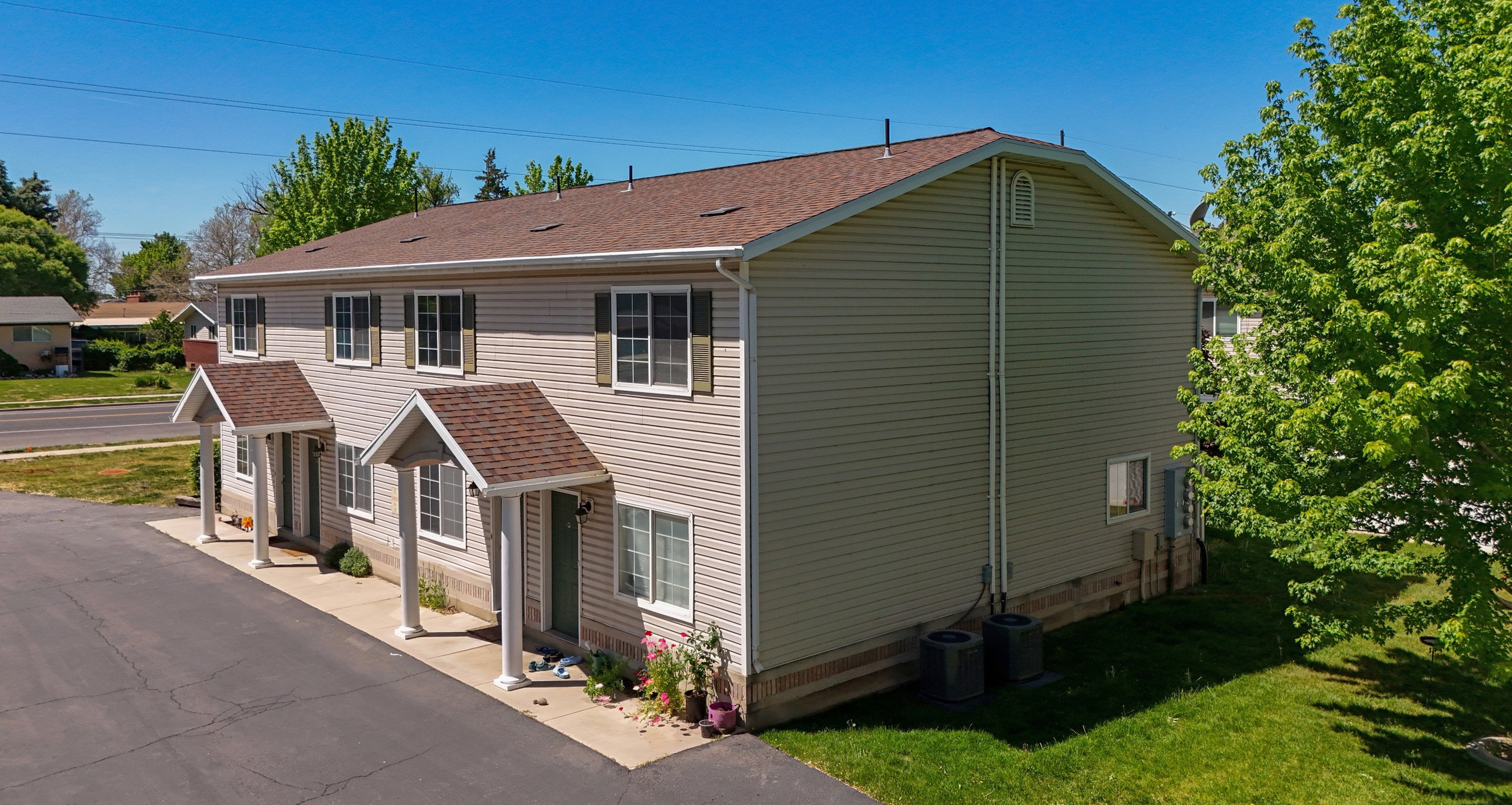 Duplex property featuring light-colored siding and a brown shingle roof