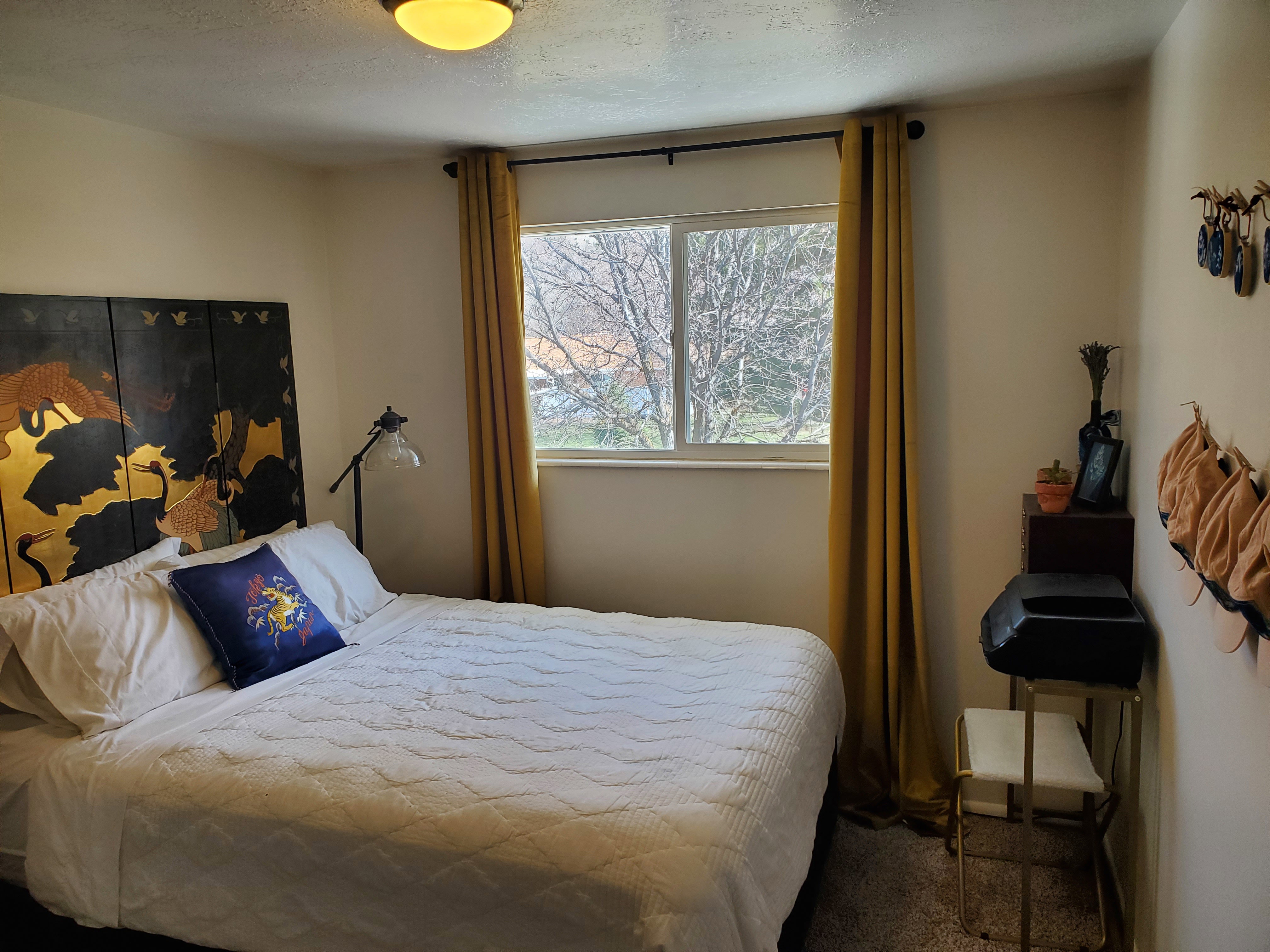 Bedroom featuring neutral wall paint, white trim, and a window with exterior tree views