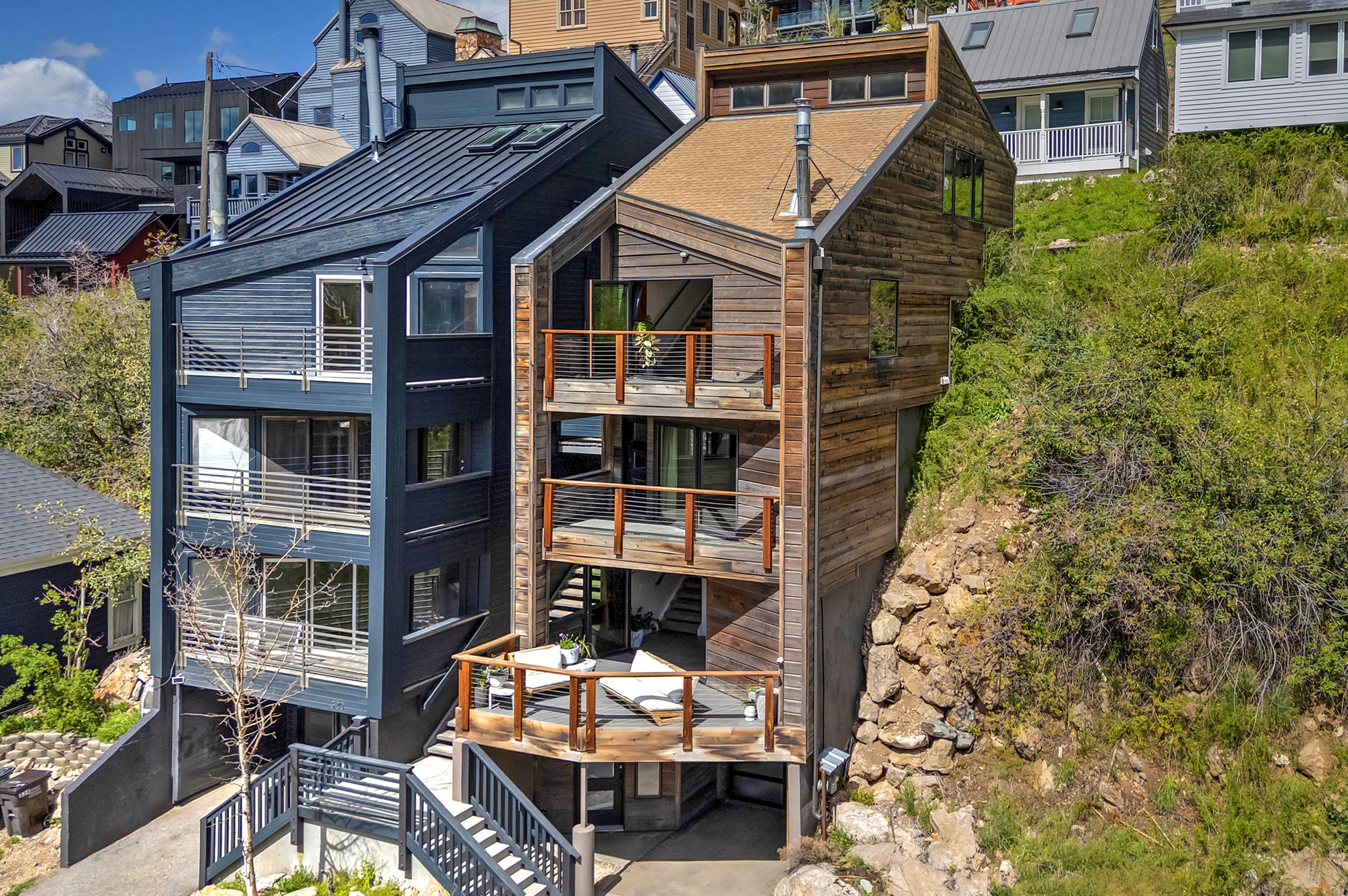 Contemporary multi-level residence featuring dark vertical siding and a metal roof