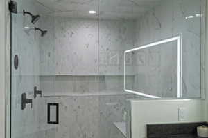 Glass-enclosed shower featuring dual matte black shower heads, white marble-look wall tiling, and a recessed product niche
