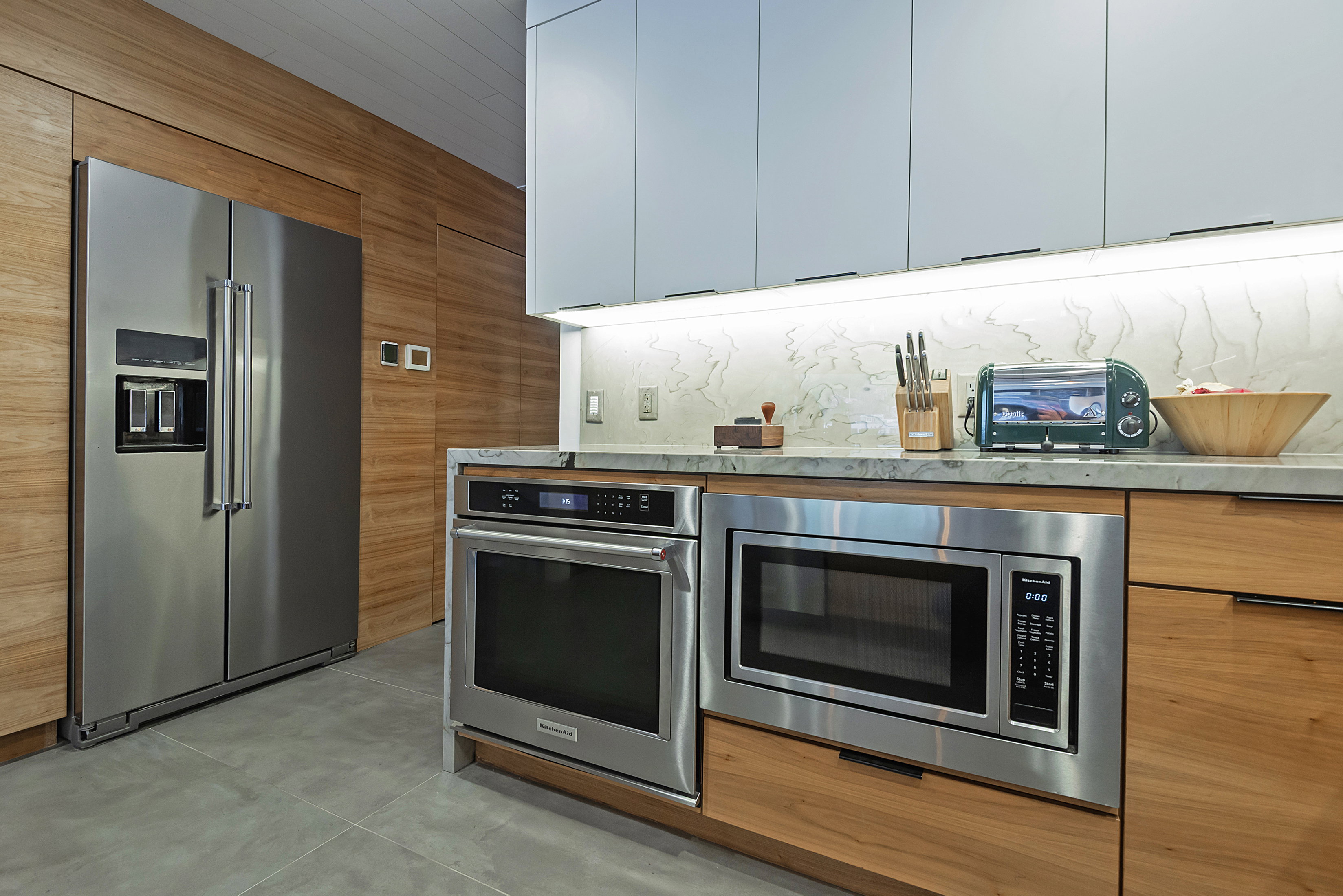 Modern kitchen featuring a stainless steel side-by-side refrigerator, built-in stainless steel microwave, and built-in stainless steel oven