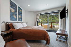 Bedroom featuring a full glass sliding door, balcony access, recessed lighting, and soft gray carpeting