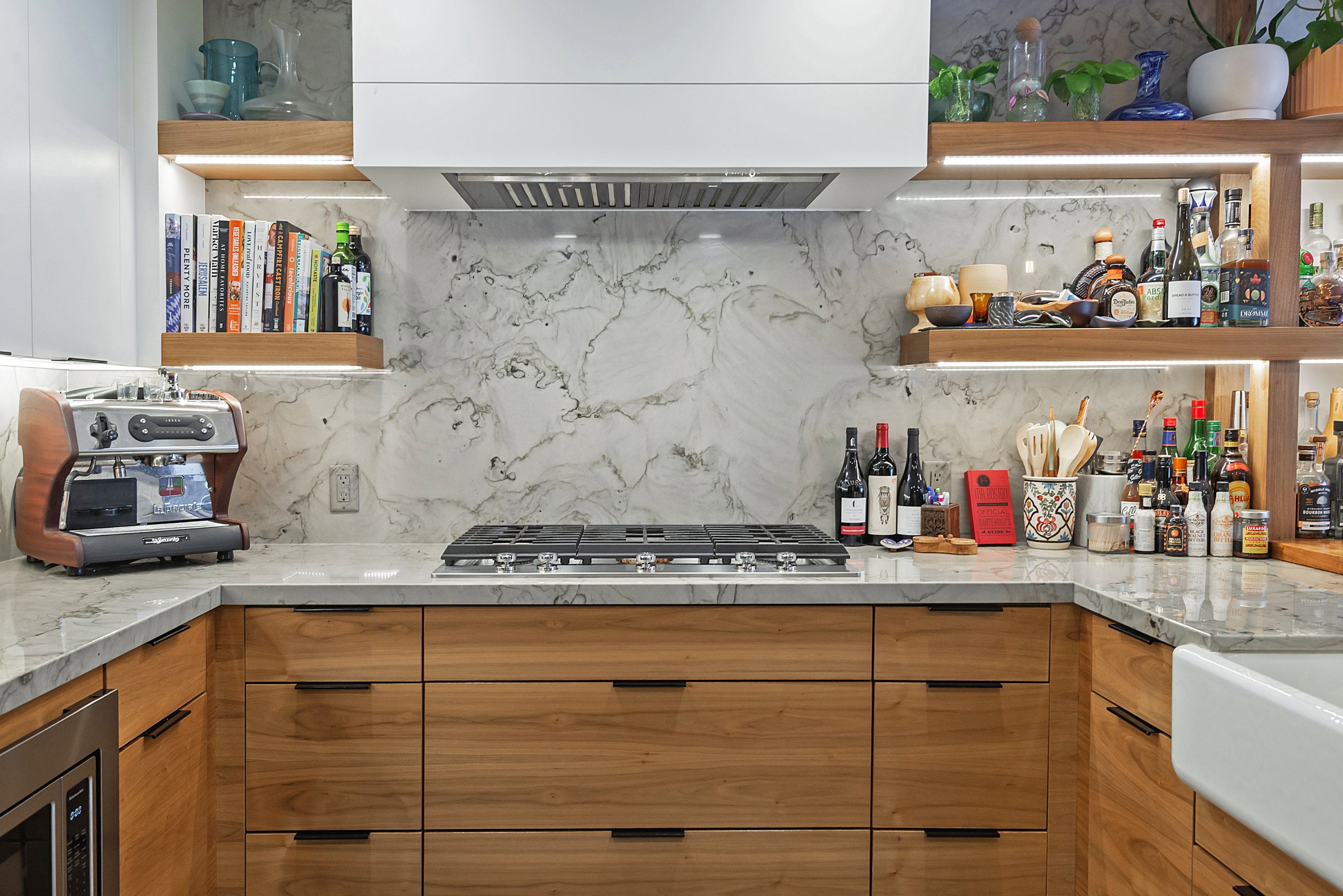 Contemporary kitchen featuring wood-finish cabinetry, light-toned countertops, and a full-height backsplash