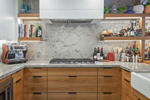 Contemporary kitchen featuring wood-finish cabinetry, light-toned countertops, and a full-height backsplash