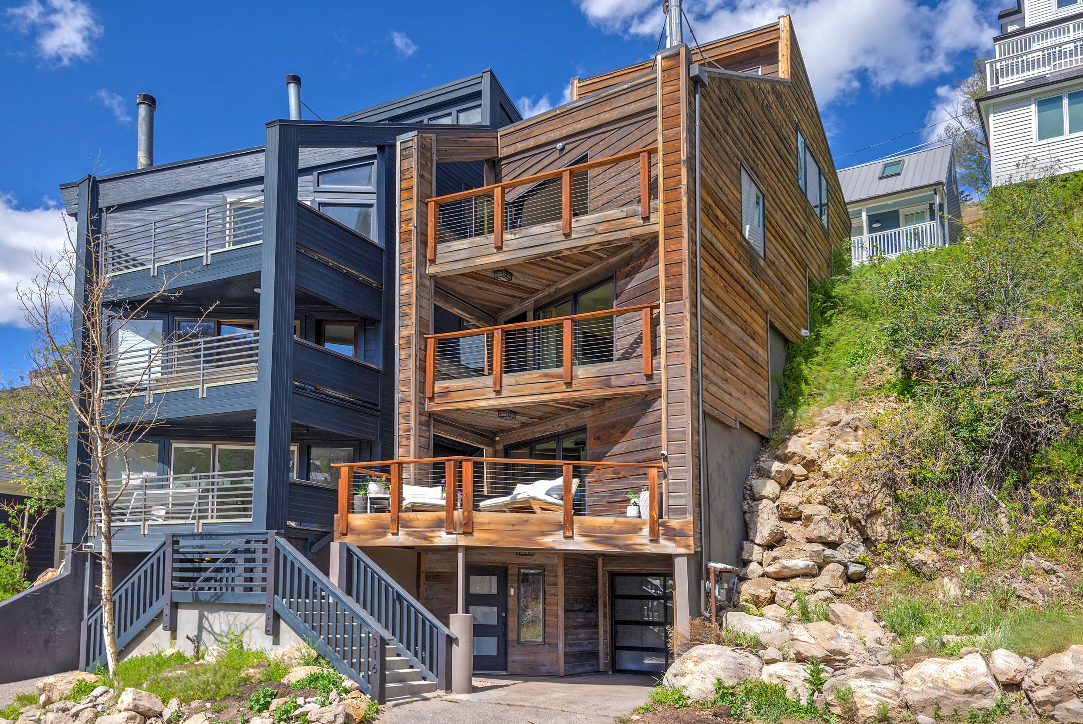 Contemporary multi-level residence featuring natural wood siding and a contrasting dark exterior