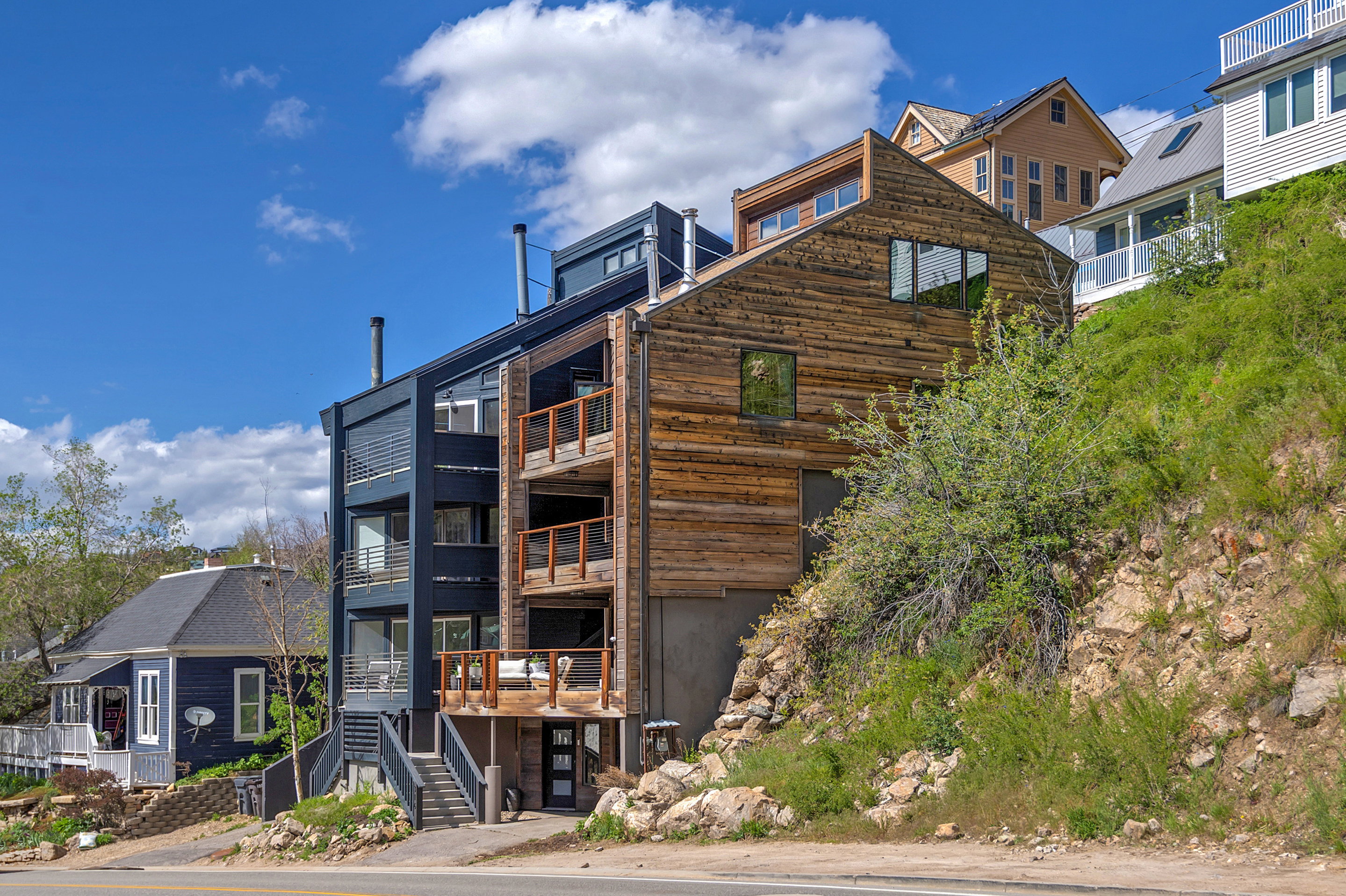 Contemporary multi-level exterior featuring dark paneled siding and natural wood cladding