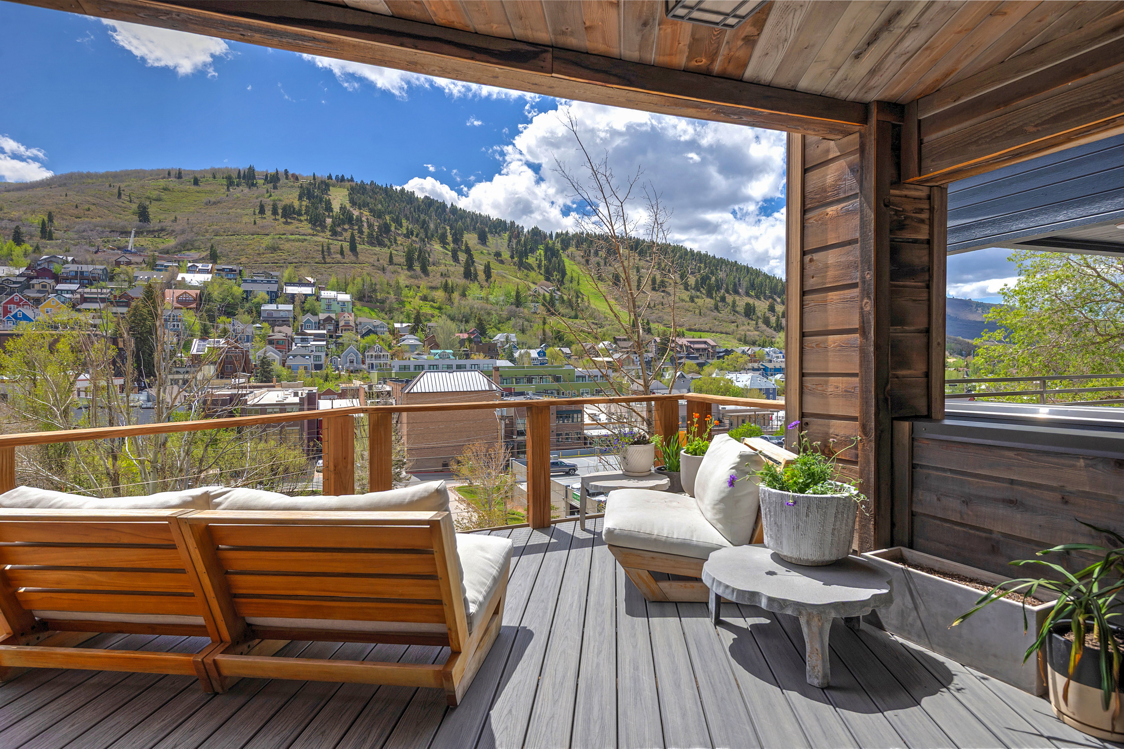 Expansive outdoor deck featuring wood-finish ceiling, wood-finish wall panels, gray composite decking, and a wood and cable railing system