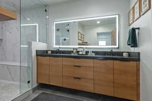 Modern bathroom featuring a floating wood-finish vanity with dual sinks and dark countertops