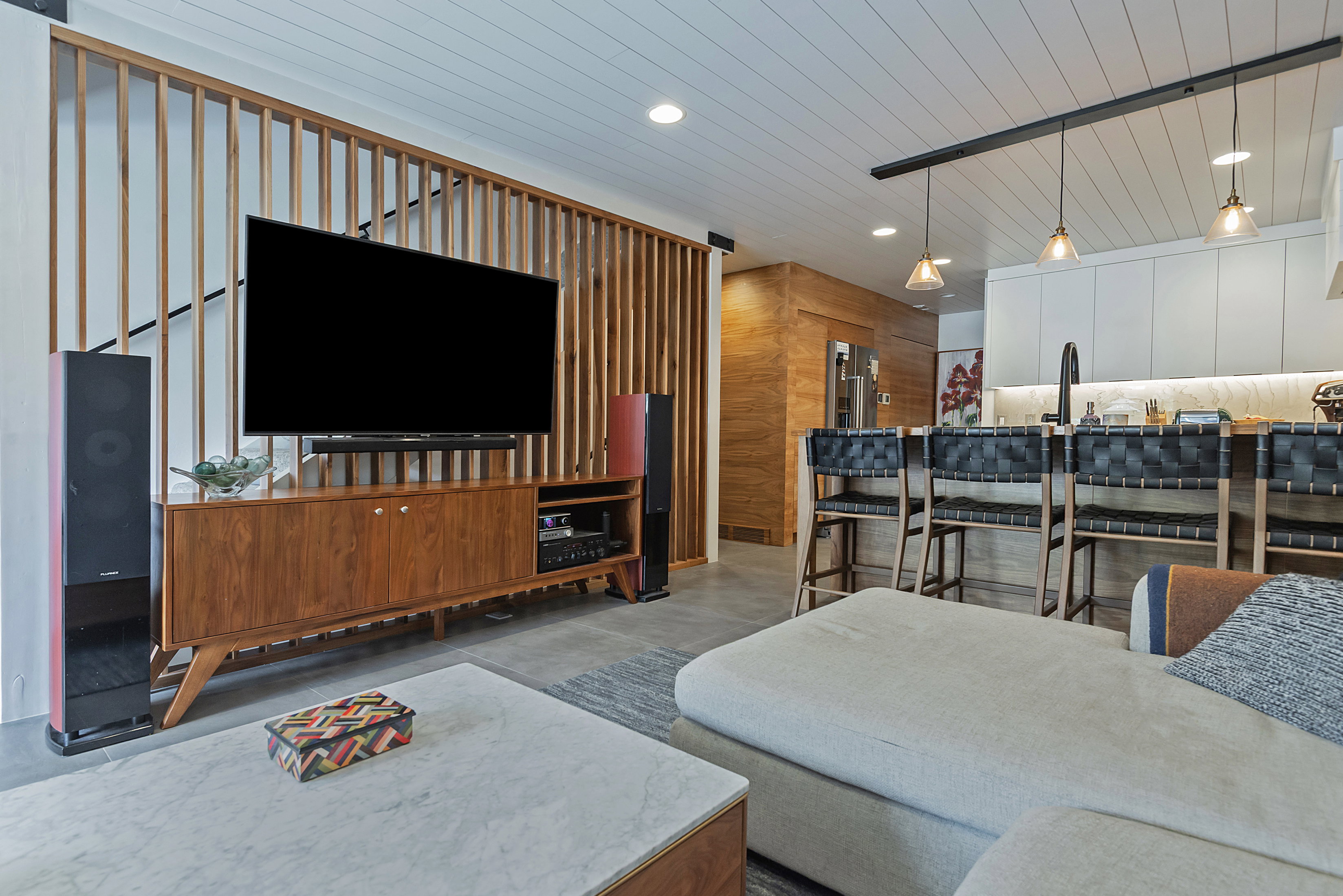 Open-concept living space featuring a wood-slat room divider, shiplap ceiling, and wood-finish flooring