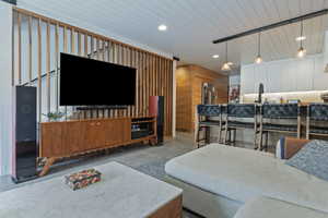 Open-concept living space featuring a wood-slat room divider, shiplap ceiling, and wood-finish flooring