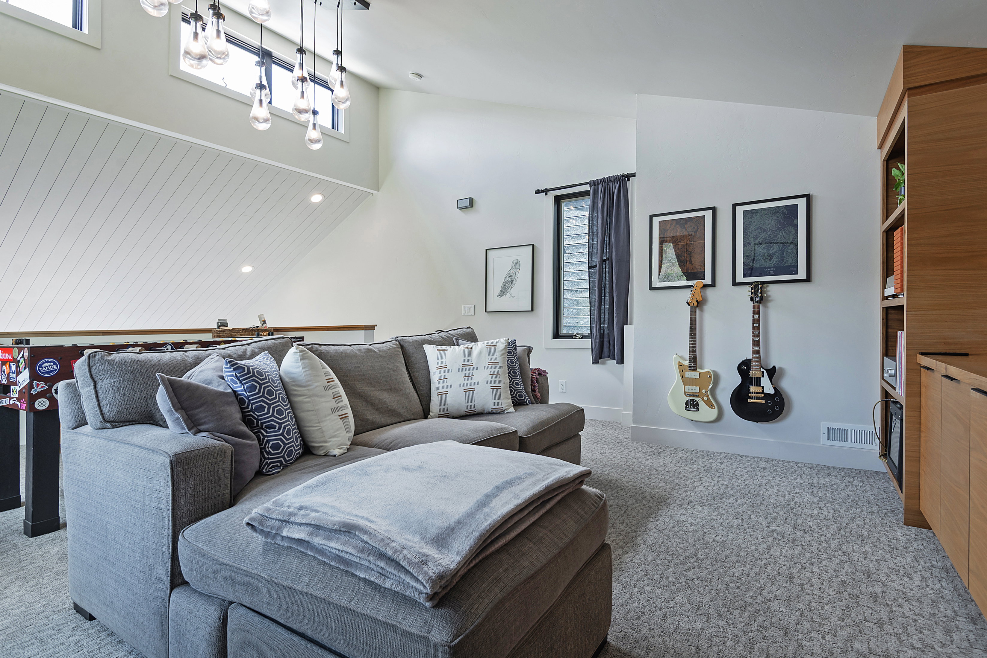 Carpeted bonus room featuring a built-in wood-finish shelving unit, high ceilings, and clerestory windows