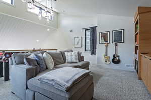 Carpeted bonus room featuring a built-in wood-finish shelving unit, high ceilings, and clerestory windows