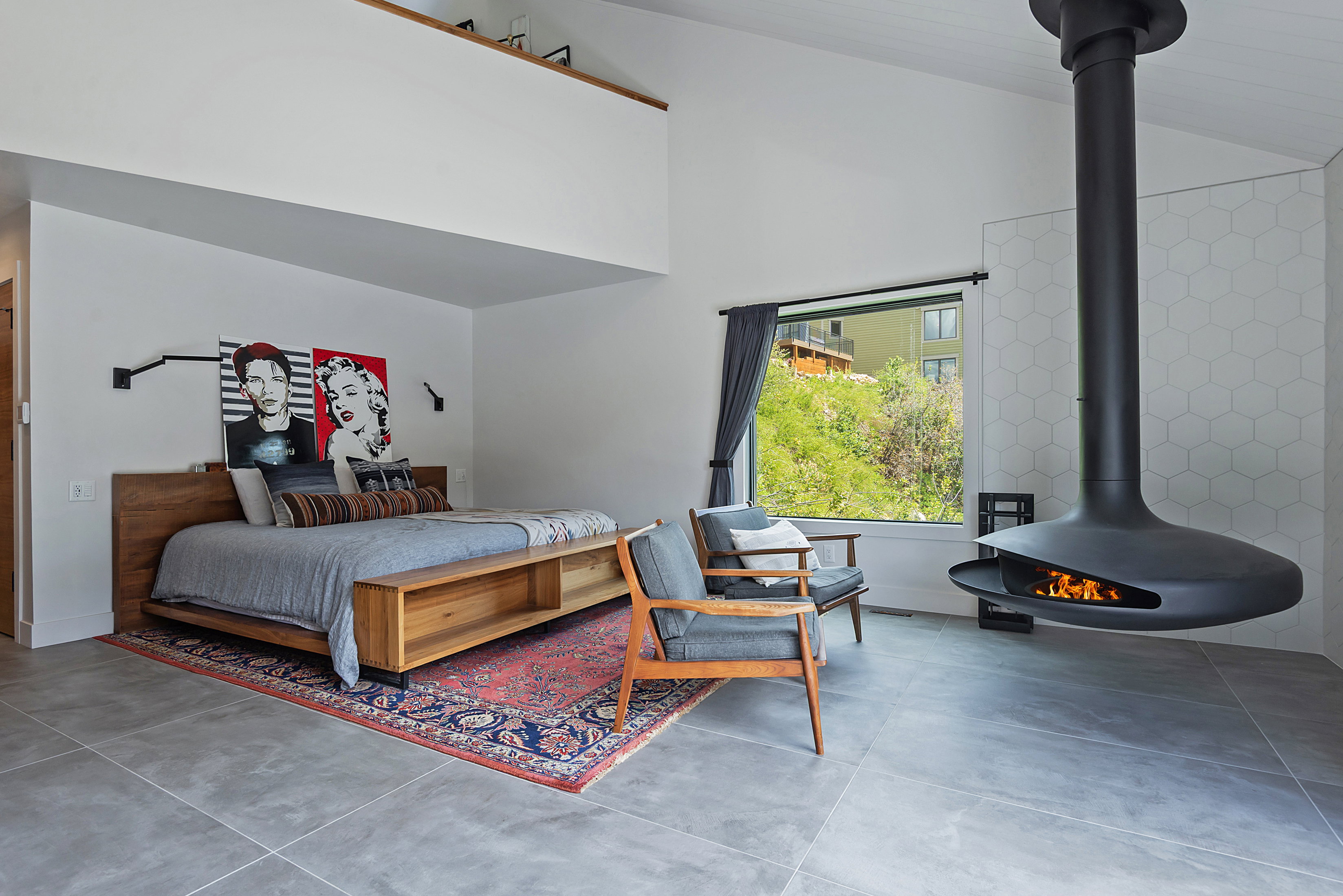 Spacious interior featuring a suspended fireplace, high ceilings, large window, and wood-finish bed frame