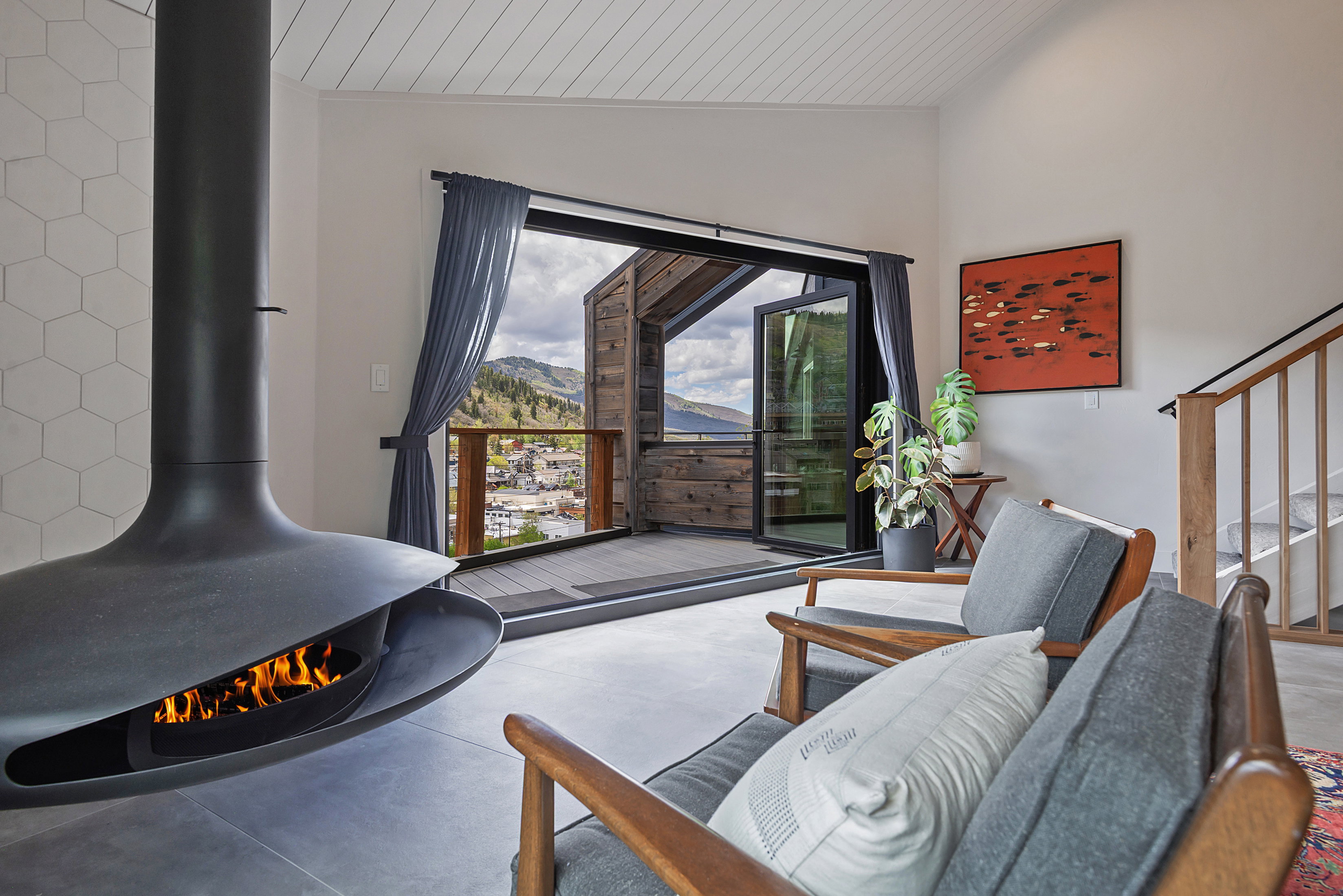 Suspended fireplace with hexagonal tile surround, wide plank wood ceiling, and direct access to an outdoor deck