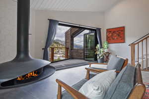 Suspended fireplace with hexagonal tile surround, wide plank wood ceiling, and direct access to an outdoor deck