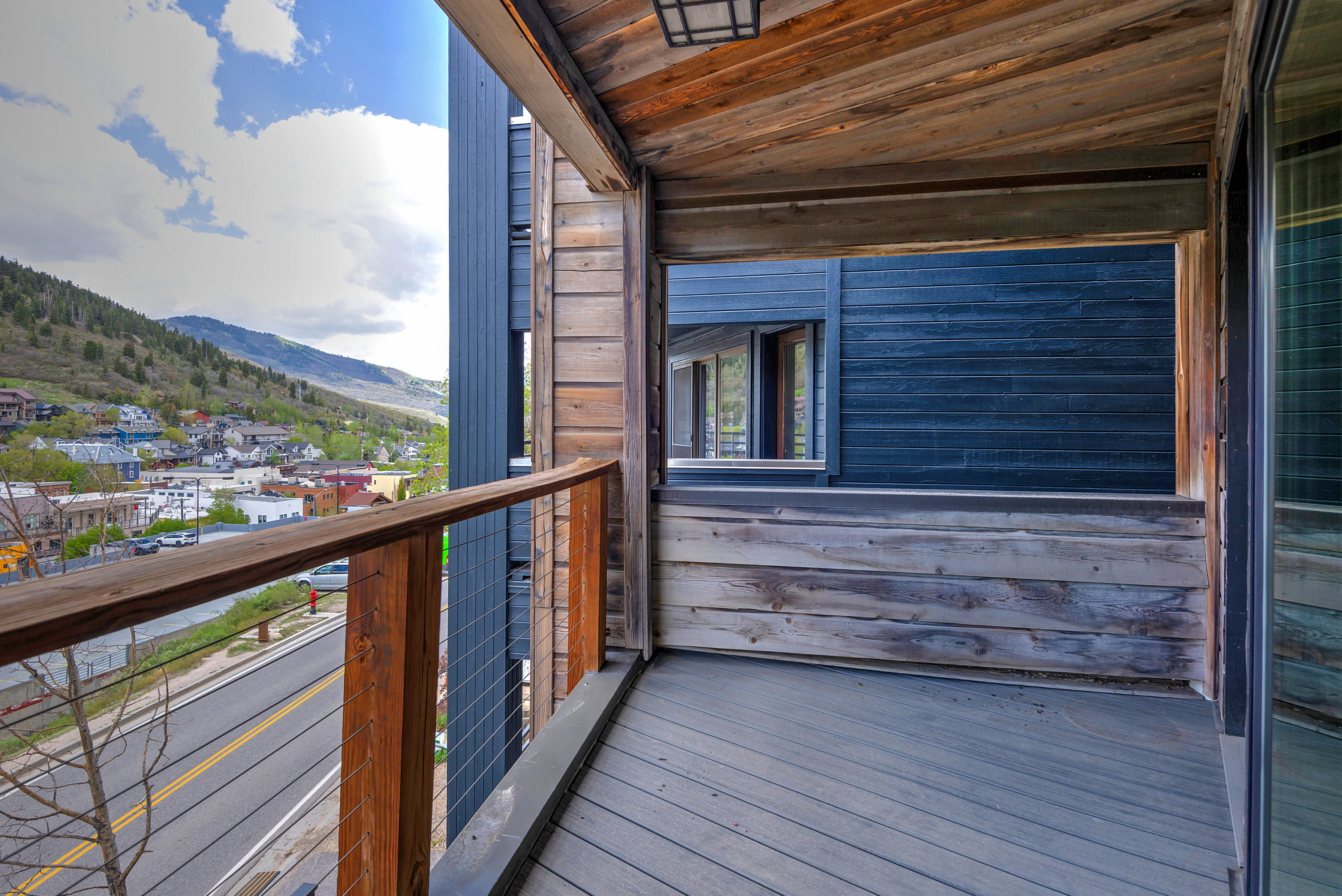 Private balcony featuring wood-finish decking and a wooden railing with cable infill