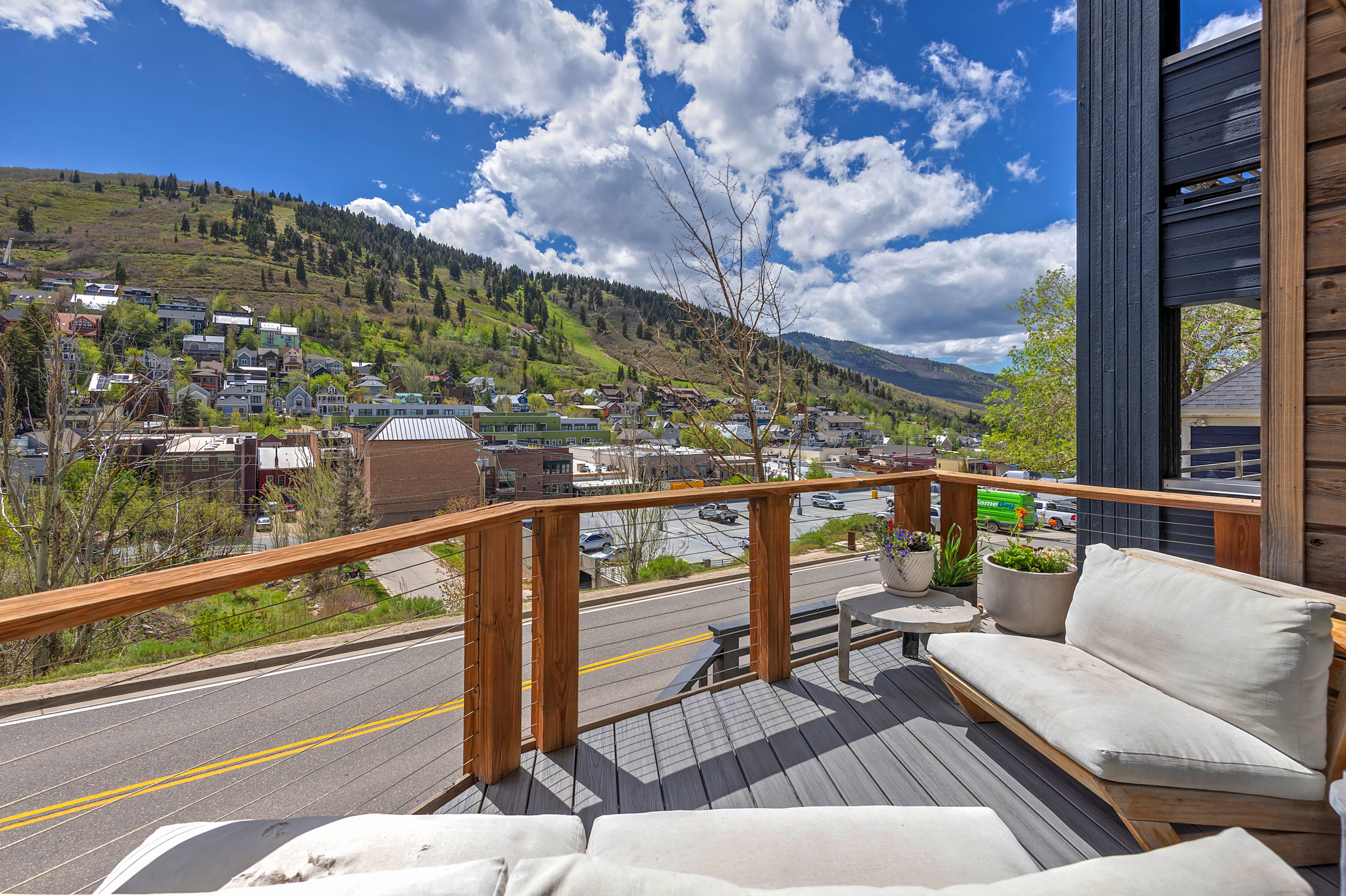 Spacious outdoor deck featuring gray composite decking, wood-toned railings with cable infill, and dark vertical siding