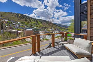 Spacious outdoor deck featuring gray composite decking, wood-toned railings with cable infill, and dark vertical siding