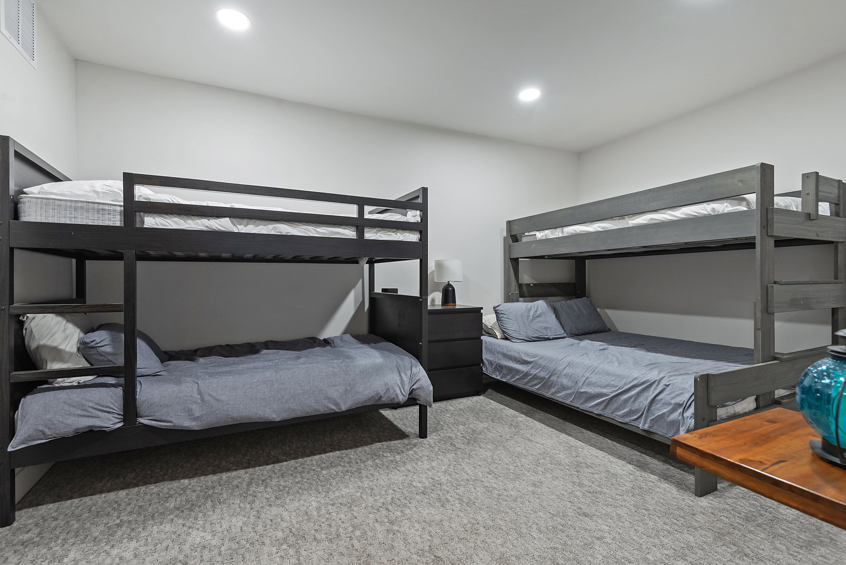 Spacious room featuring two sets of bunk beds, recessed lighting, neutral wall finishes, and light grey carpeted flooring