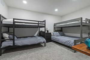 Spacious room featuring two sets of bunk beds, recessed lighting, neutral wall finishes, and light grey carpeted flooring