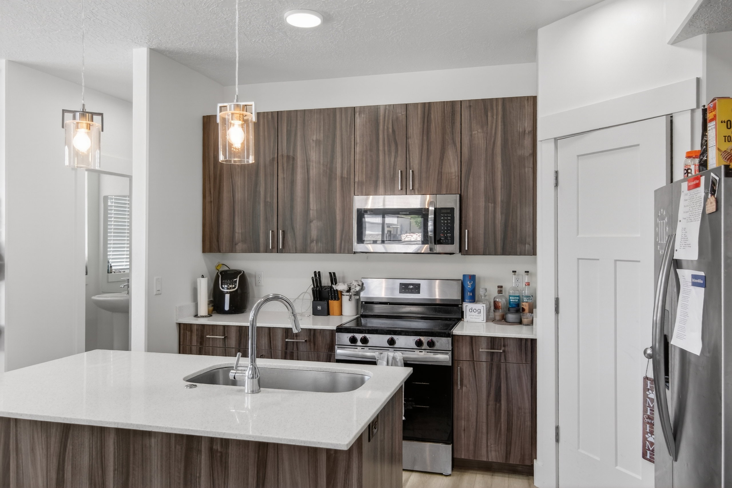 Modern kitchen featuring wood-finish cabinetry, stainless steel appliances, and a central island with an undermount sink