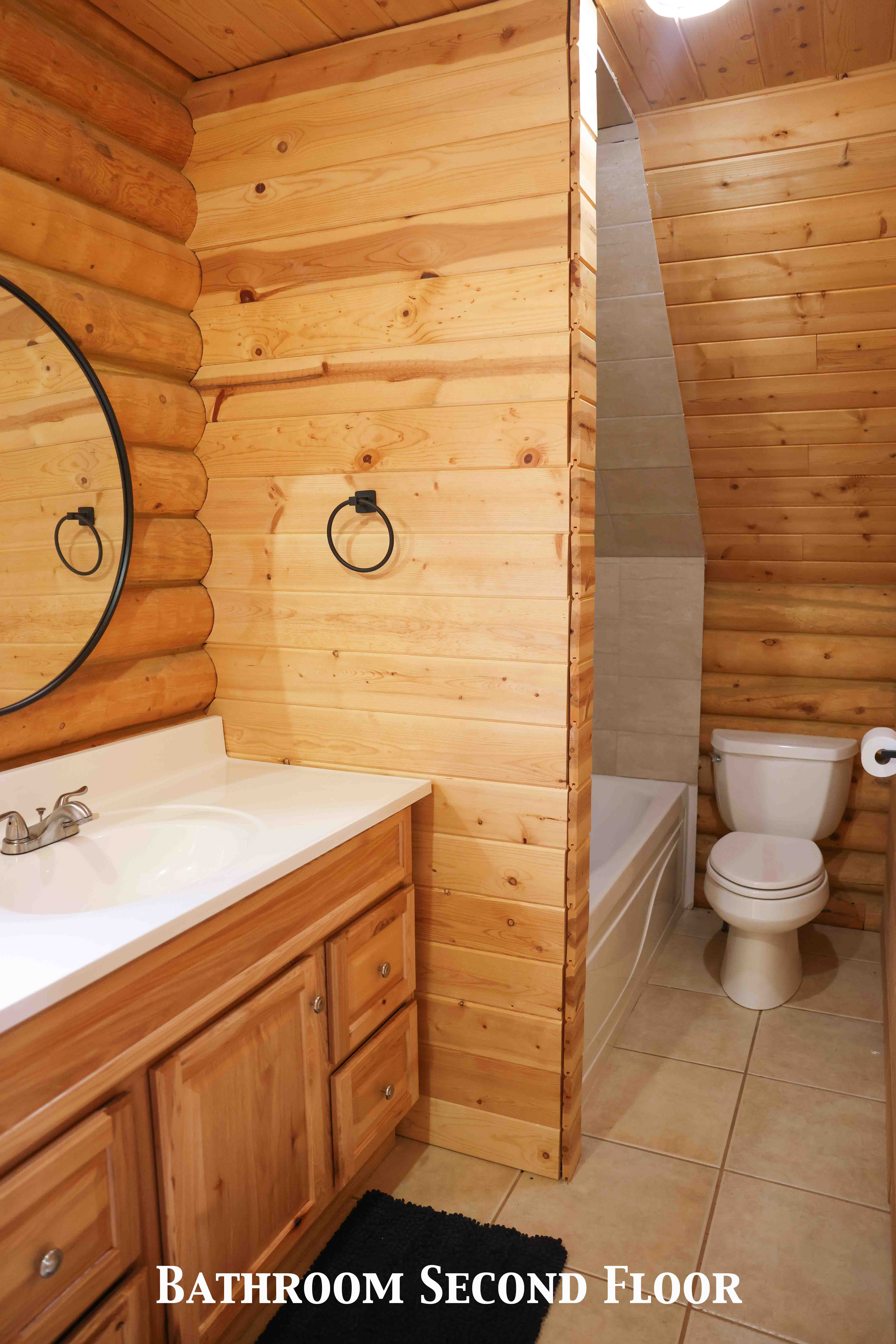 Bathroom featuring wood-finish walls, a vanity with a solid surface countertop and integrated sink, and tile flooring