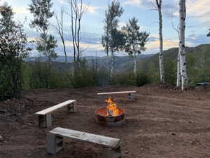 Outdoor fire pit area with three wooden benches on a natural ground surface