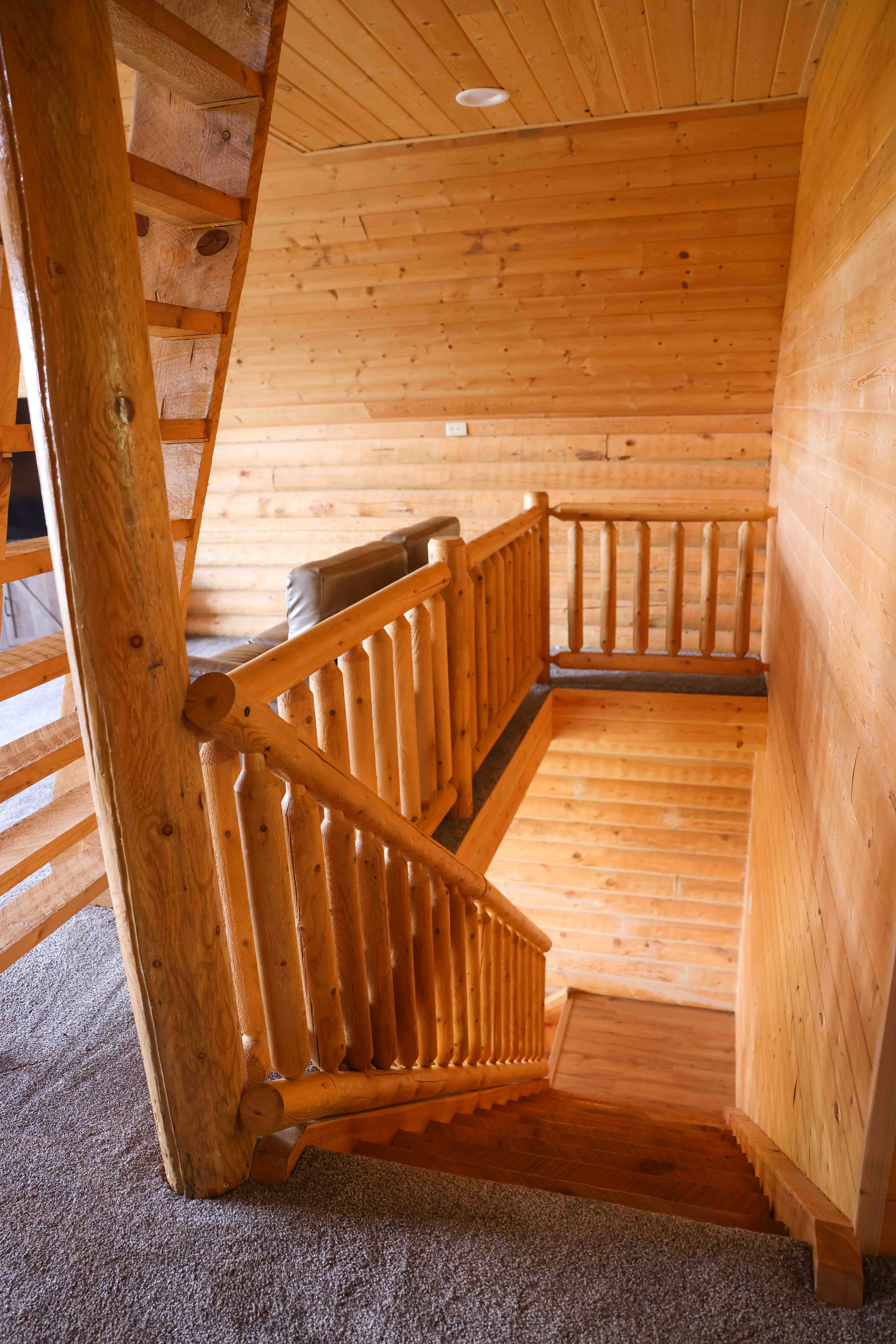 Rustic staircase featuring log-style railings and banisters