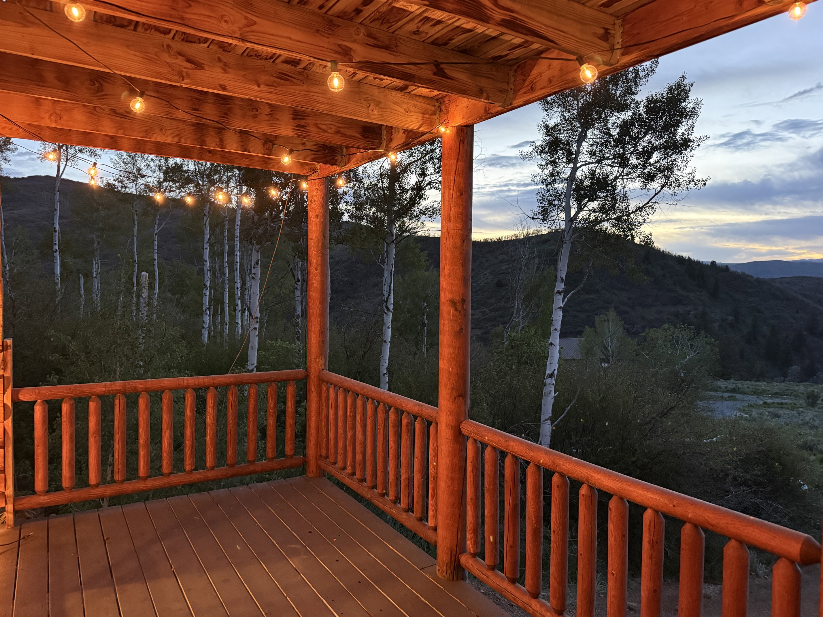 Covered outdoor deck featuring exposed wood beams and string lighting