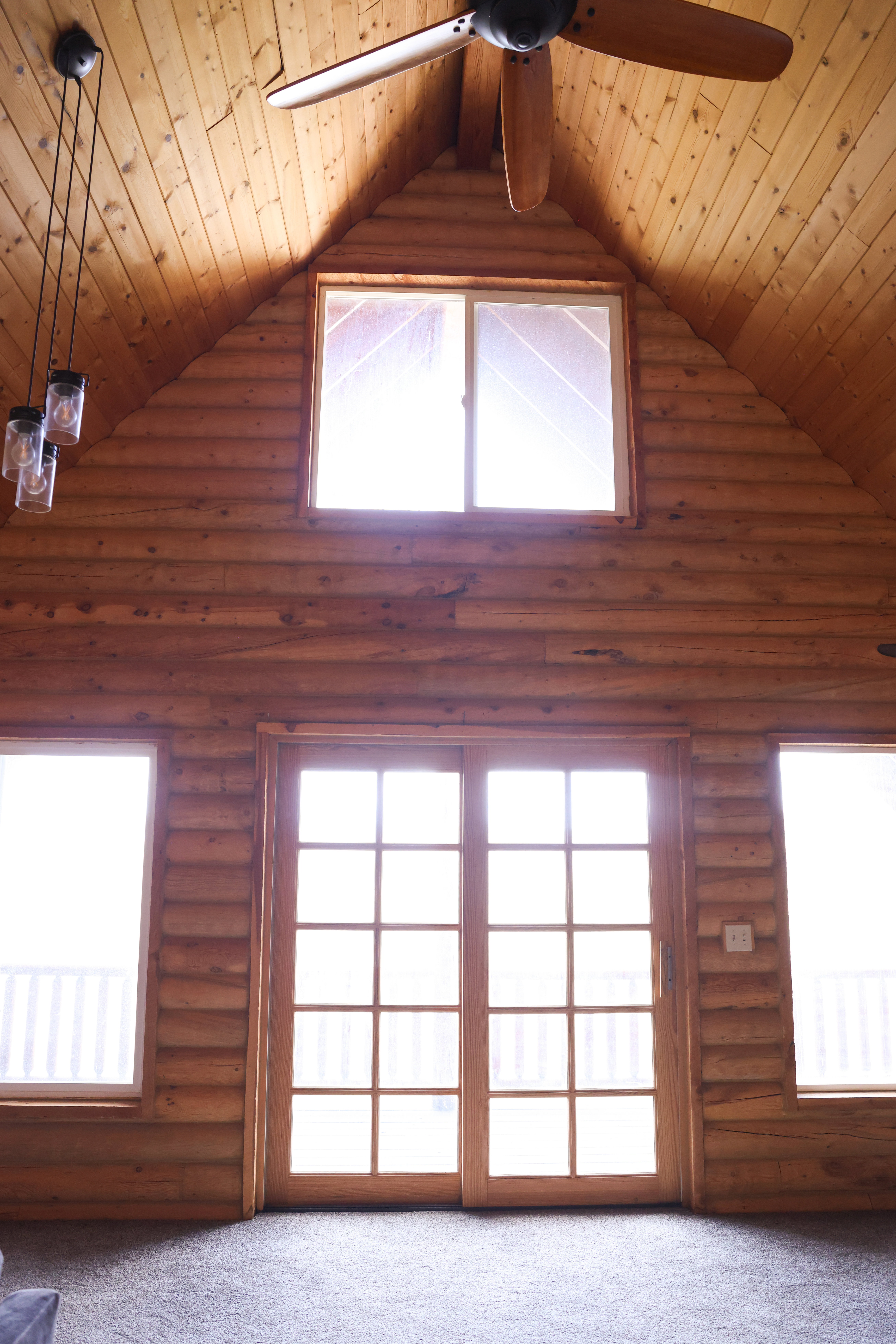 Vaulted wood-paneled ceiling with an exposed beam and ceiling fan