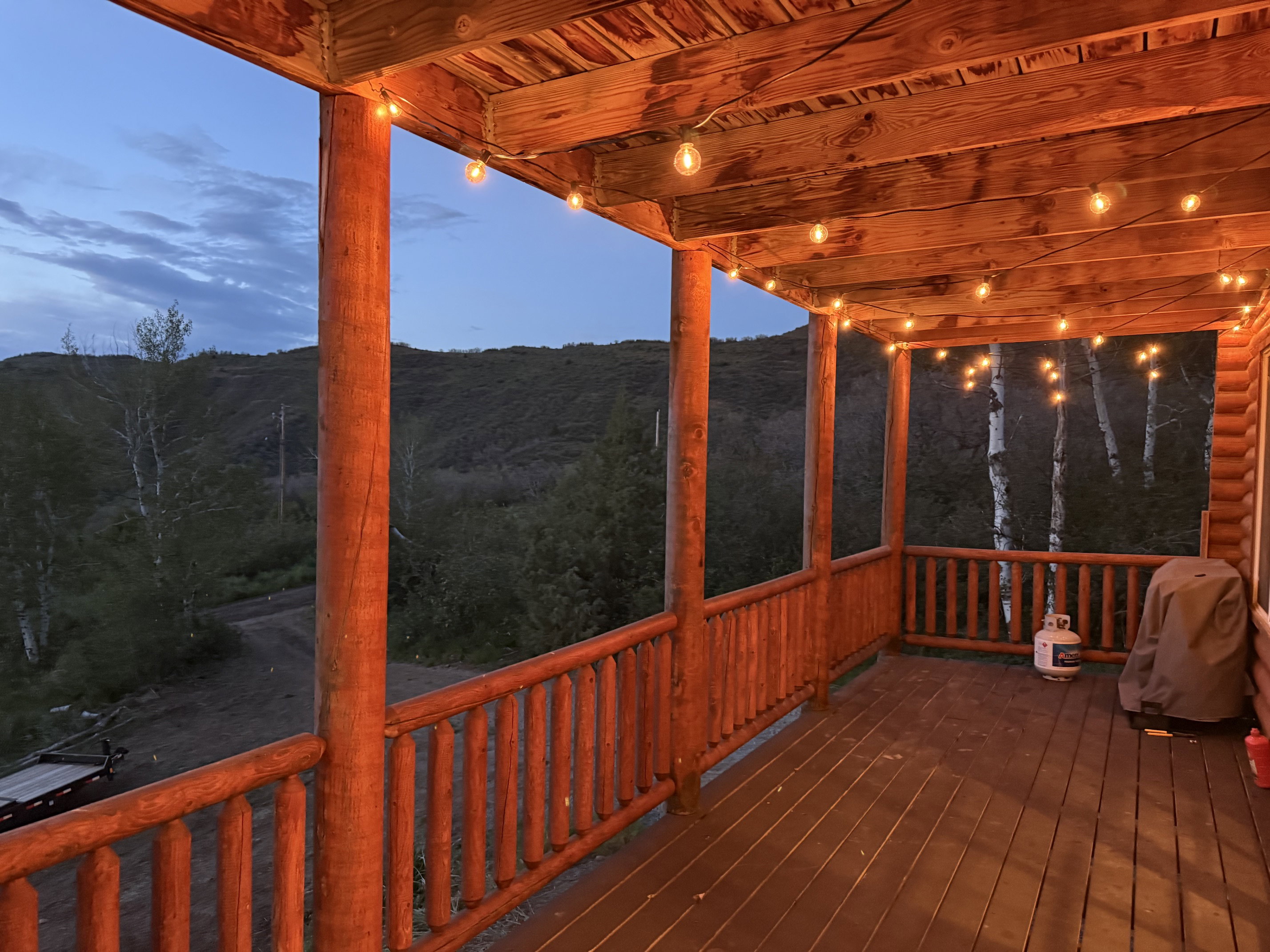 Expansive covered deck featuring a wood-finish floor, wood posts, and string lighting