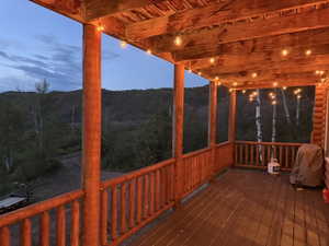Expansive covered deck featuring a wood-finish floor, wood posts, and string lighting