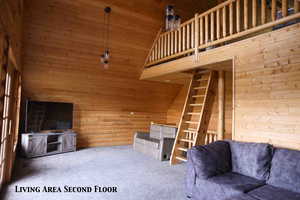 Open-concept living space featuring wood paneling, sloped ceilings, and wood-finish flooring