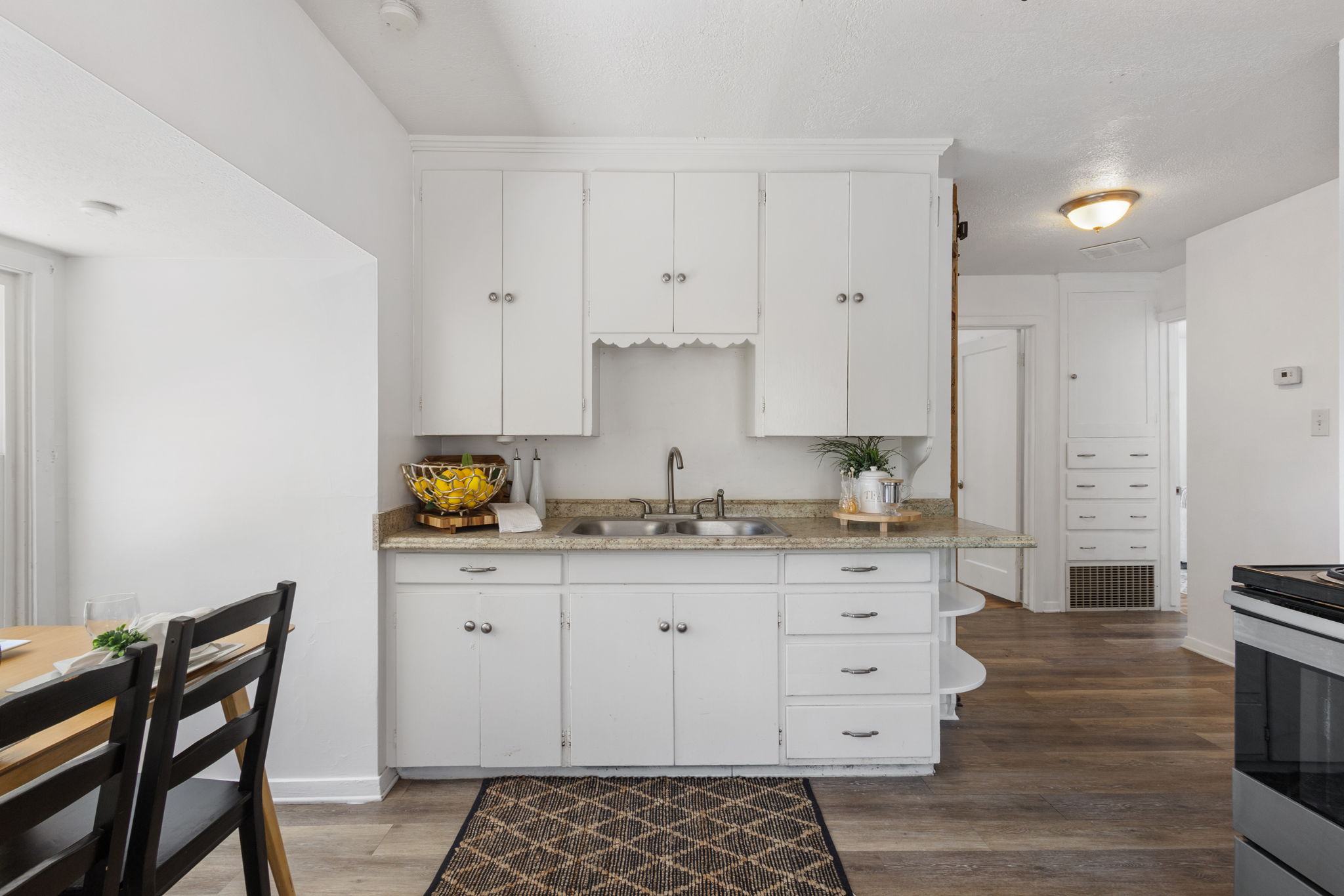 Kitchen featuring white cabinetry, a dual basin stainless steel sink, and a light-toned countertop